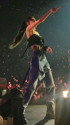 a woman standing on top of a stage with her arms out in front of the crowd