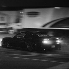 a black car driving down a street at night