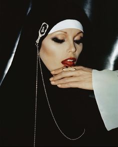 a woman wearing a nun outfit and holding her hand over her face with a chain around her neck