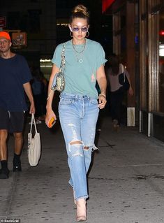 a woman walking down the street in ripped jeans