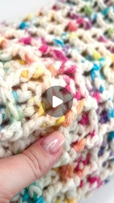 a hand is holding a crochet bag with a button in it's center