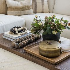 a tray topped with jewelry and flowers on top of a table next to a couch