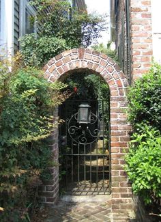 an iron gate in front of a brick building with ivy growing on the walls and around it