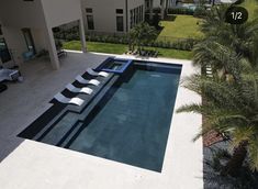 an aerial view of a swimming pool with chaise lounges in the foreground