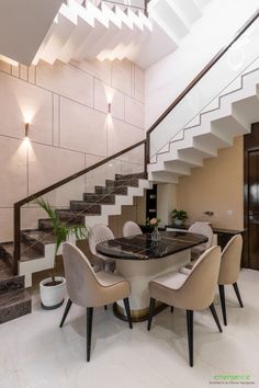 a dining room table with four chairs under a stair case next to a staircase leading up to the second floor