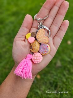 a hand holding a keychain that has various cookies and tassels on it