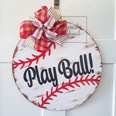 a wooden sign that says play ball with a bow hanging on the front door handle