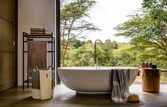 a large bath tub sitting on top of a wooden floor next to a bathroom window