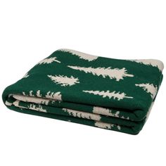 the green and white blanket is folded on top of each other, with trees printed on it