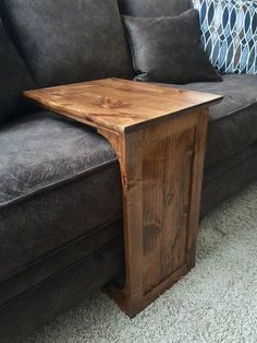 a wooden table sitting on top of a couch next to a blue throw pillow in a living room