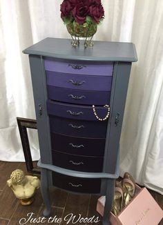 a purple and blue dresser with flowers on top, next to a pink flower vase