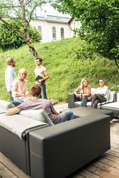 a group of people are sitting on couches outside