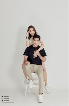 a man sitting on top of a chair next to a woman in black shirt and khaki pants