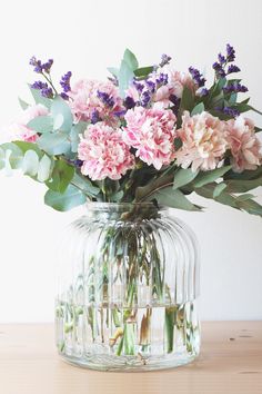 a vase filled with lots of flowers on top of a wooden table