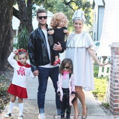 a man, woman and two children standing on the sidewalk