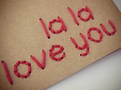 the words i love you spelled out on a piece of brown paper with red string