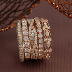 a stack of gold and diamond rings sitting on top of a brown table next to a net