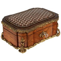 an ornately decorated wooden box sitting on top of a white surface with gold trimmings