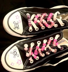 two black and white shoes with pink bows on the laces are sitting next to each other