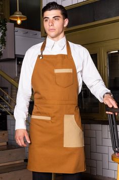 a man in an apron is standing with his hands on the back of a chair