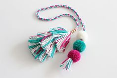 two tasselled pom - poms hanging from a string on a white surface