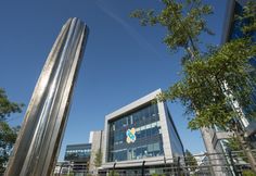 an office building with large metal sculptures in the foreground and trees on either side