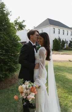 a bride and groom kissing in front of a large house