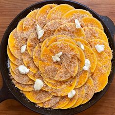 an iron skillet filled with sliced oranges and white cream on top of a wooden table