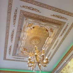 a chandelier hanging from the ceiling in a room with gold and white decor