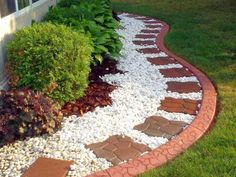 a garden area with gravel, rocks and plants on the side of a home's front yard