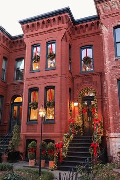 a large red brick building with wreaths and lights on it's front door