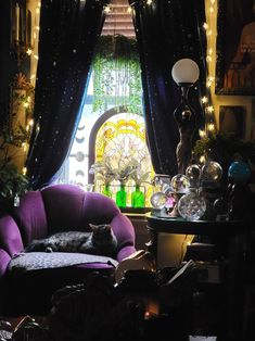 a cat is sleeping on a purple chair in front of a window with fairy lights