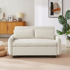 a living room with a white couch and potted plant on the floor next to it