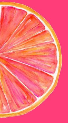 a grapefruit cut in half on a pink background