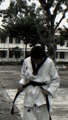 a man standing in front of a tree holding a black belt