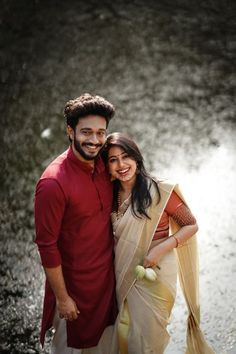 a man and woman standing next to each other in the water with their arms around each other