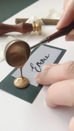 a person holding a pair of scissors and writing on a piece of paper next to a stamp