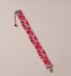 a red and white beaded wristband with hearts on it, attached to a metal keychain