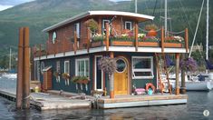 a houseboat with flowers on the deck is docked at a dock in front of mountains