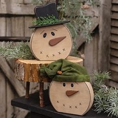 two wooden snowmen sitting on top of a tree stump