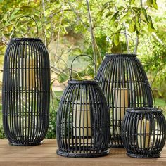 three black lanterns sitting on top of a wooden table