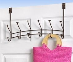 a pink purse hanging on a hook in front of a white door with two hooks