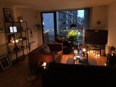 a living room filled with furniture next to a large window covered in candles and pictures