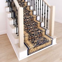 a carpeted staircase with black railings and blue rug on the bottom handrail