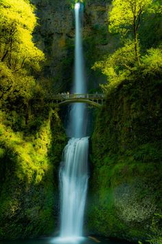 a large waterfall with a bridge over it