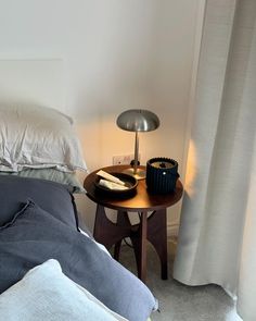 a bed with two pillows and a lamp on the end table next to it,