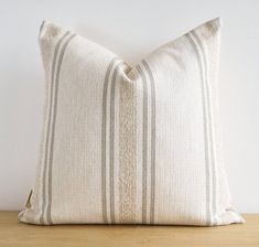 a white and grey striped pillow sitting on top of a wooden table