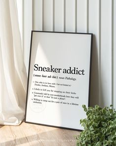 a sign that reads sneaker addit next to a potted plant on the floor