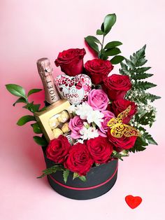 valentine's day flowers and chocolates in a heart shaped box on a pink background