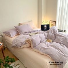 an unmade bed with purple sheets and pillows